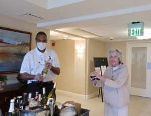 photo of a Roland Park Place staff member serving wine to a senior resident