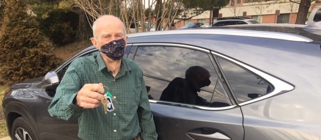 photo of a senior man standing outside the driver's side door of a car, holding the keys up