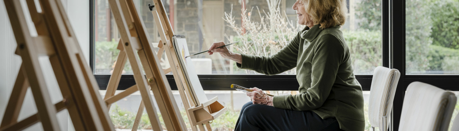 senior woman painting on an easel at Roland Park Place