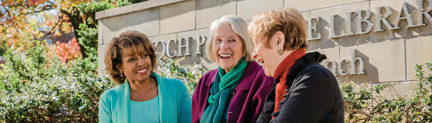 group of three senior women sitting in front of the Enoch Pratt Free Library