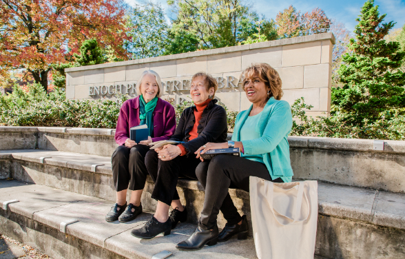 three senior living residents sitting on the steps in front of the Enoch Pratt Free Library in Baltimore