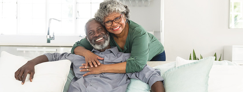 photo of a happy senior couple sitting on a couch smiling