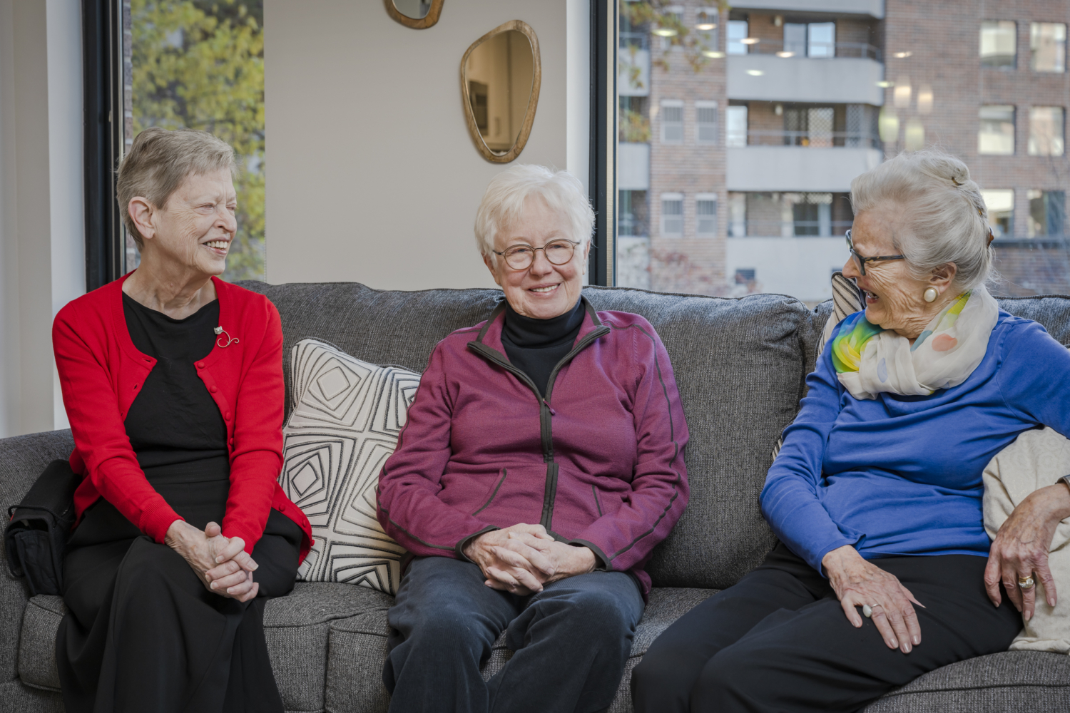 three senior women sitting together on a couch and smiling
