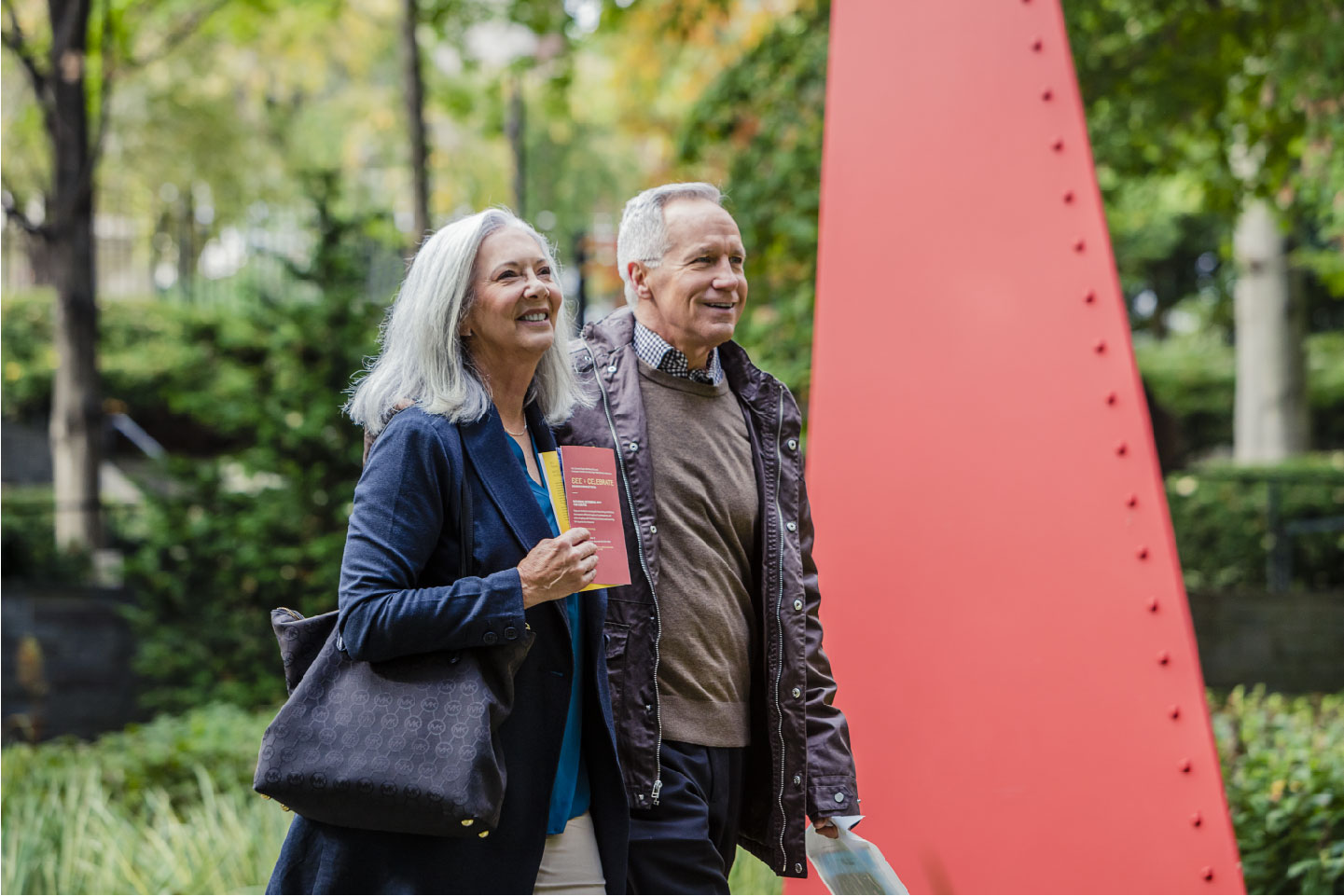 Image of a happy senior couple taking a walk outside while the woman holds her coffee. 