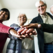 Image of a group of happy seniors with hands together.