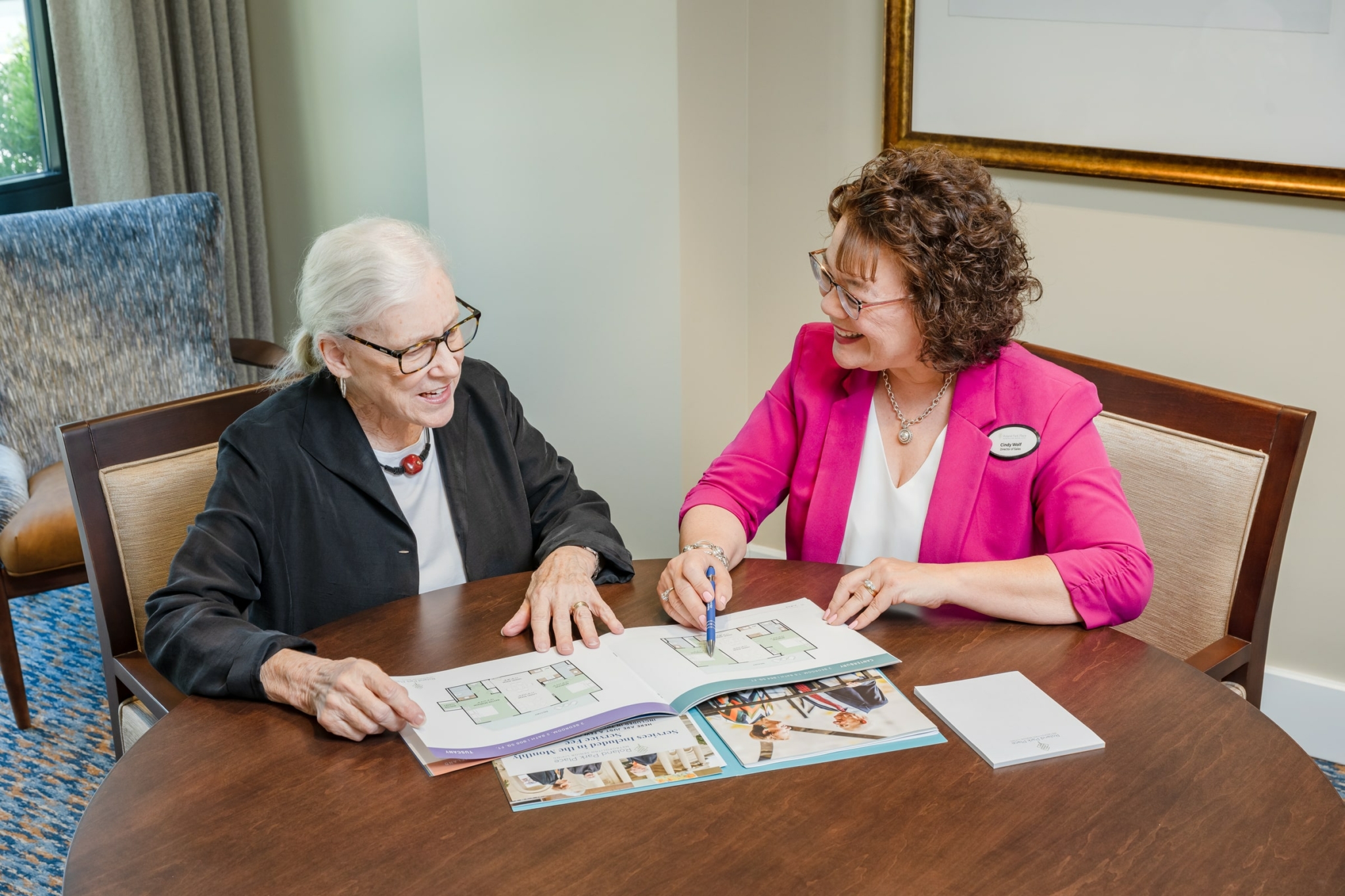 a senior woman looking through the floor plan offerings at Roland Park Place with a staff member