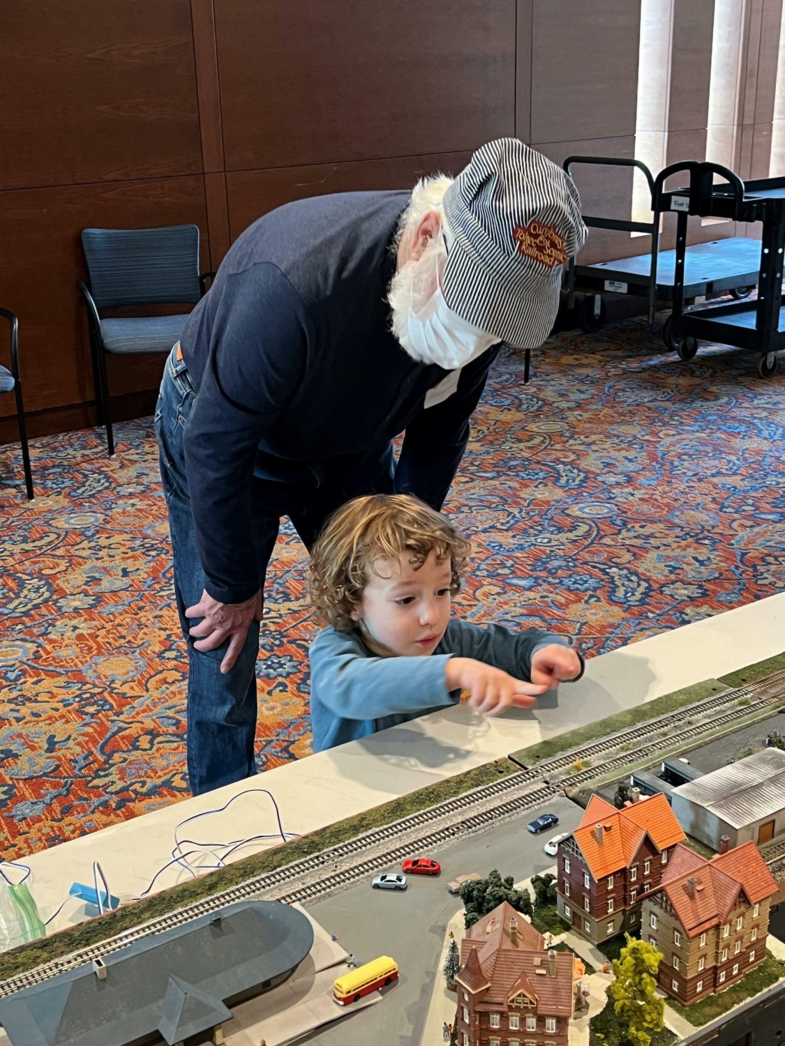 young child pointing at a train set at the holiday model train show at our senior living community