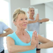 a group of four seniors practicing yoga in a fitness studio