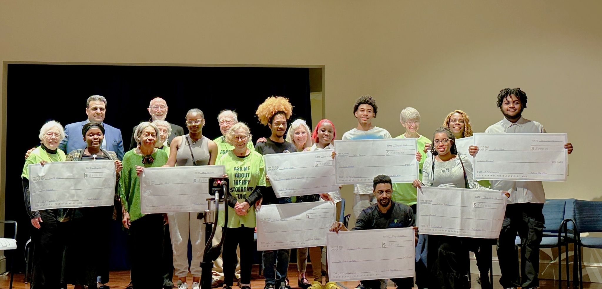group photo of those involved in Roland Park Place’s scholarship program holding oversized checks